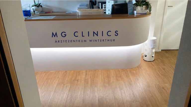 Modern medical clinic reception desk with MG Clinics branding, wooden flooring, and organized front desk area